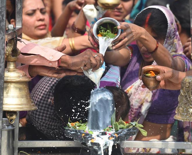 people offering water milk on shiva linga