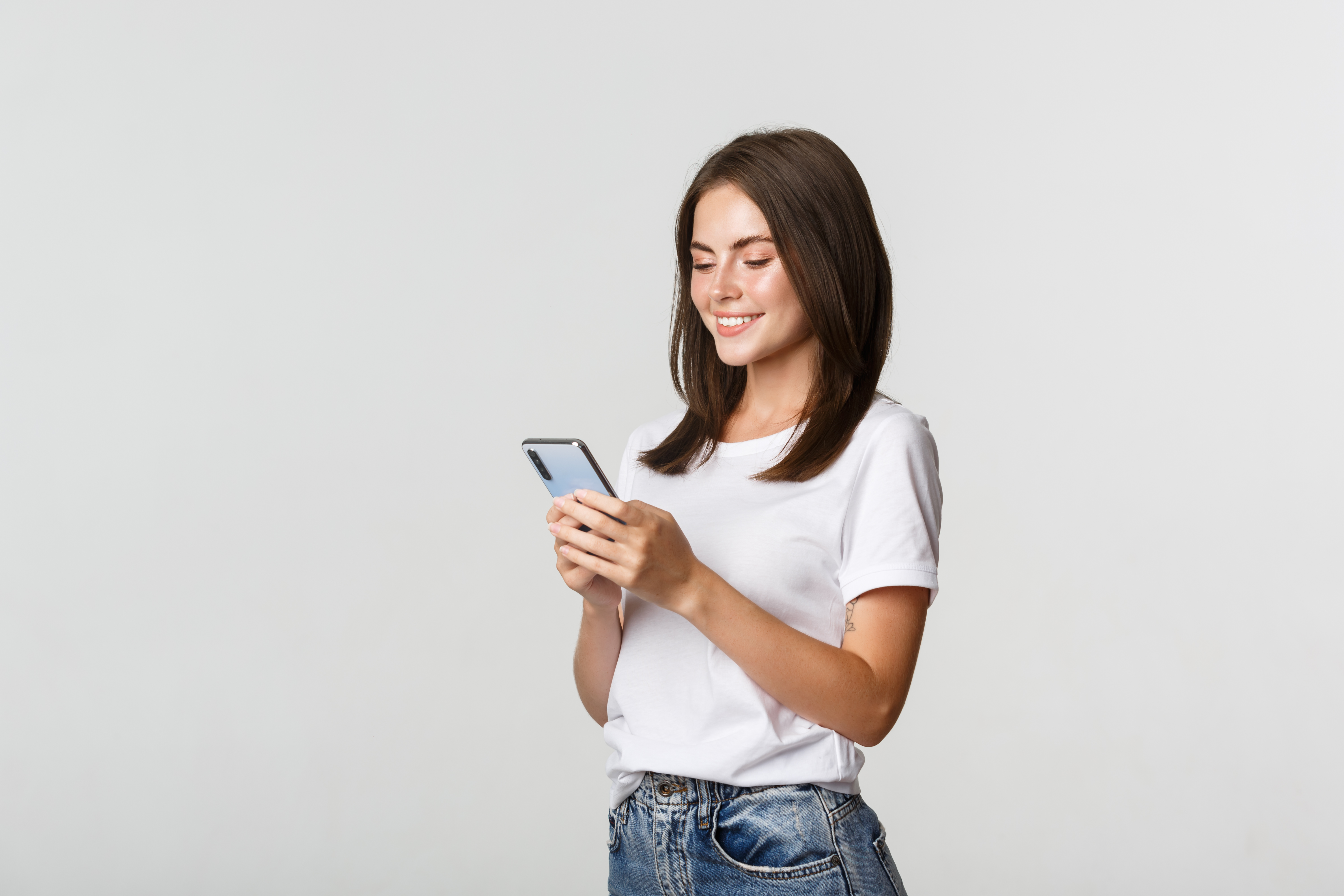 beautiful-smiling-girl-using-mobile-phone-looking-smartphone-pleased