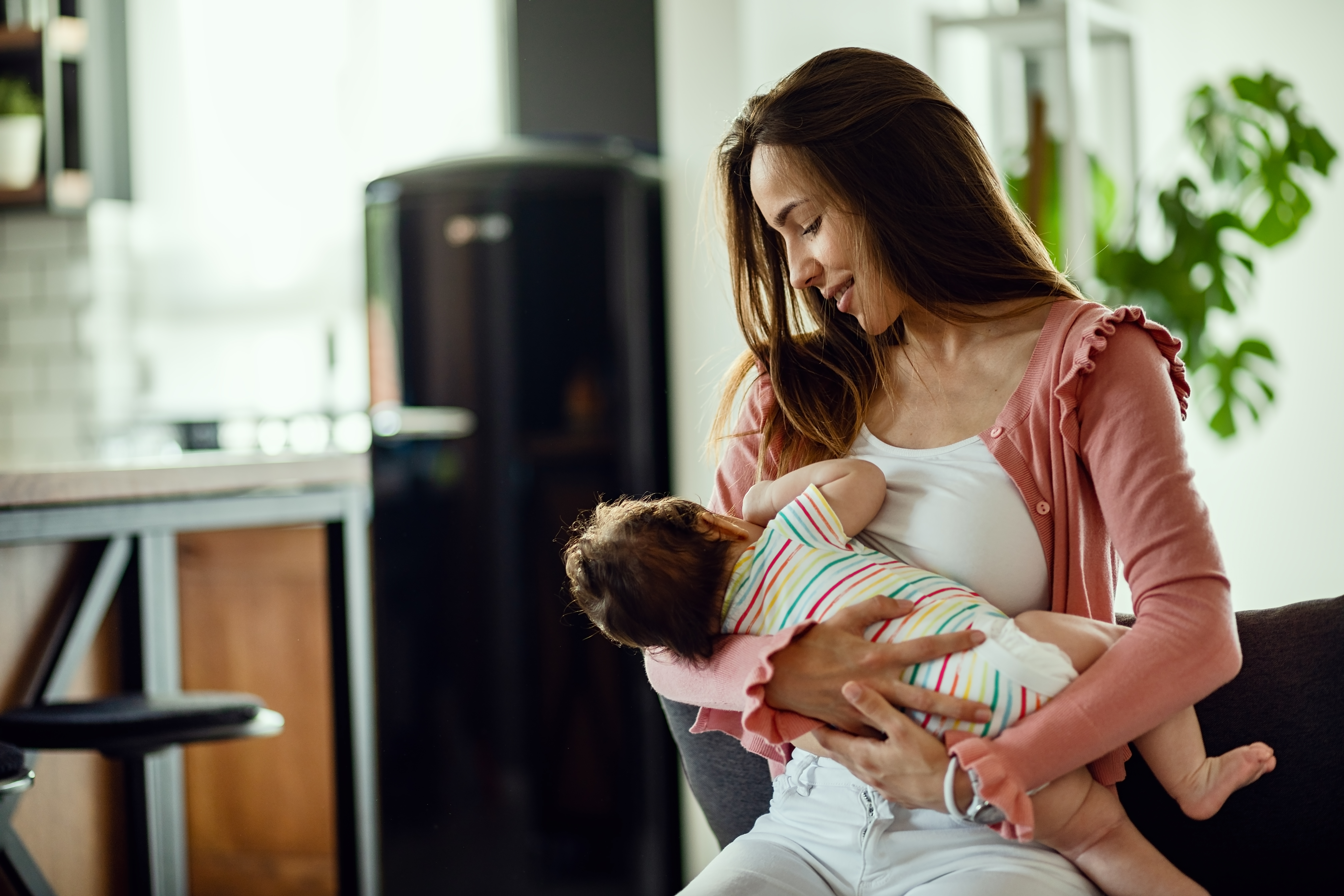 smiling-mother-breastfeeding-her-baby-daughter-while-being-home