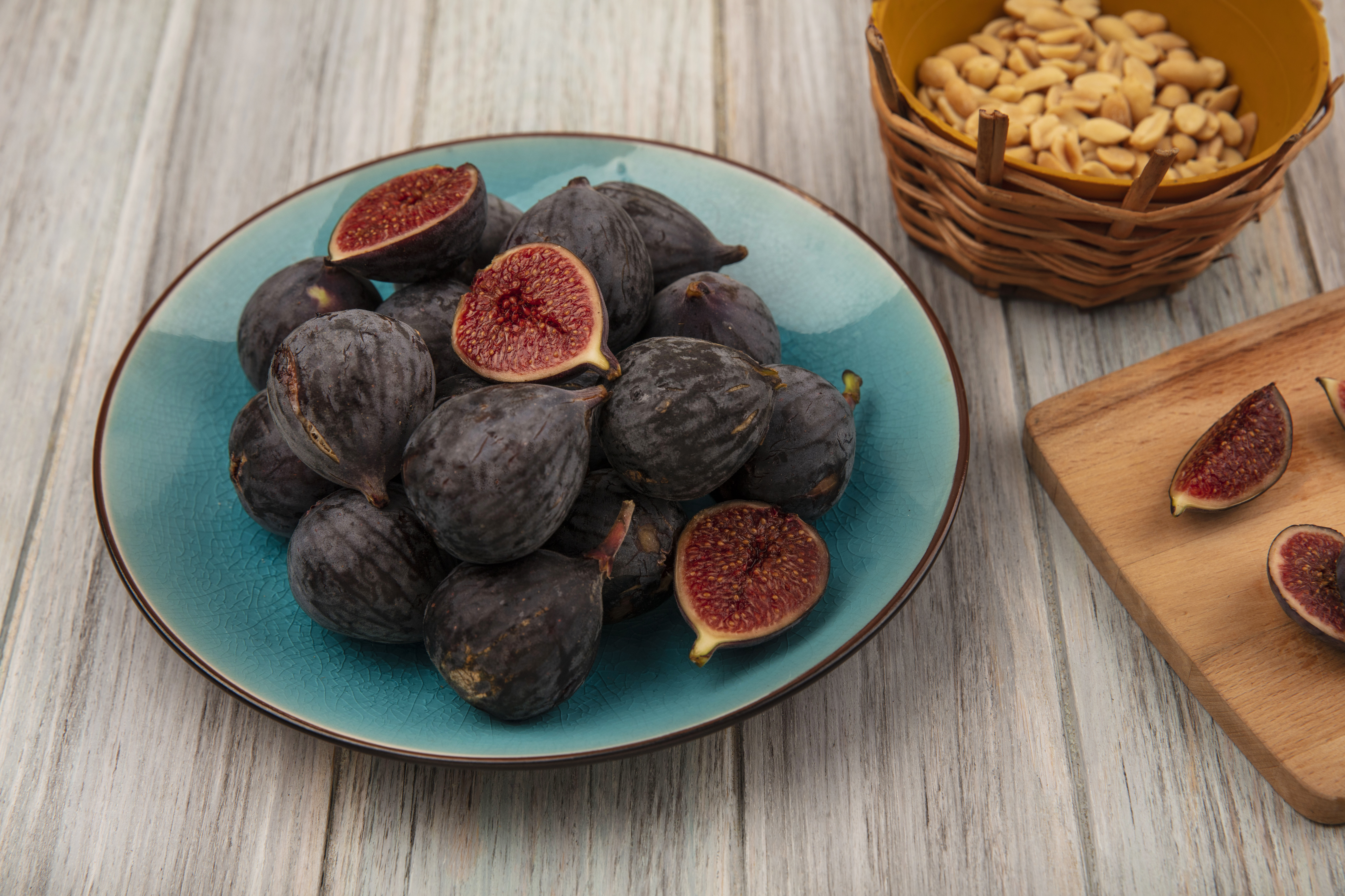 top-view-dark-purple-mission-figs-blue-bowl-with-slices-black-figs-wooden-kitchen-board-grey-wooden-surface