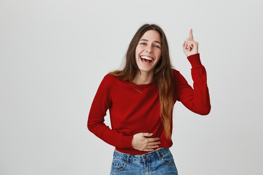 laughing-happy-attractive-woman-touching-belly-pointing-finger-up_176420-17338