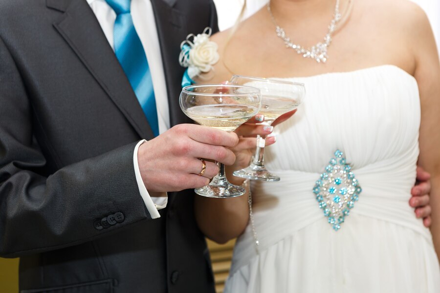 glasses-wine-hands-bride-groom-wedding-party_474467-1916