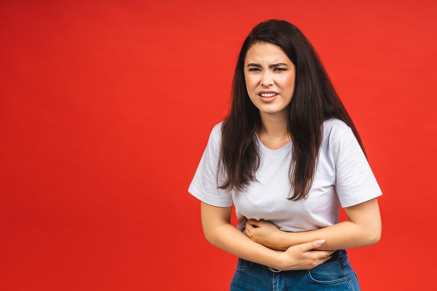 young-beautiful-woman-having-abdominal-pain-isolated-red-background_255757-10876