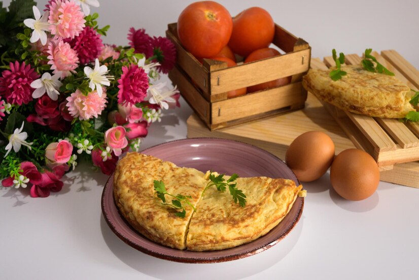 closeup-shot-half-omelet-two-eggs-tomatoes-bouquet-flowers-table_665346-17070