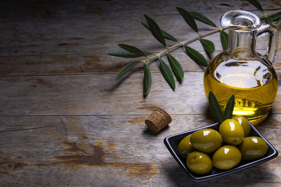 tasty-looking-olives-extra-virgin-olive-oil-olive-leafs-dark-wooden-background_181624-43771