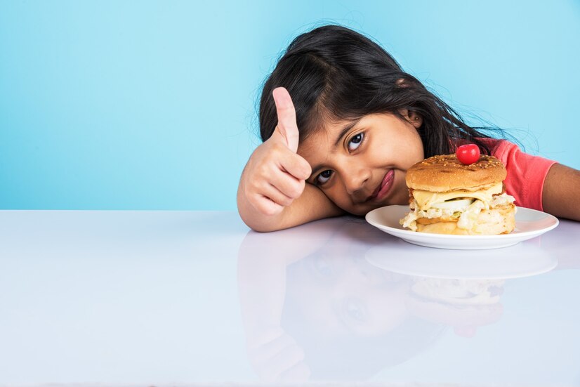 cute-indian-asian-little-girl-eating-tasty-burger-sandwich-pizza-plate-box-standing-isolated-blue-yellow-background_466689-12098