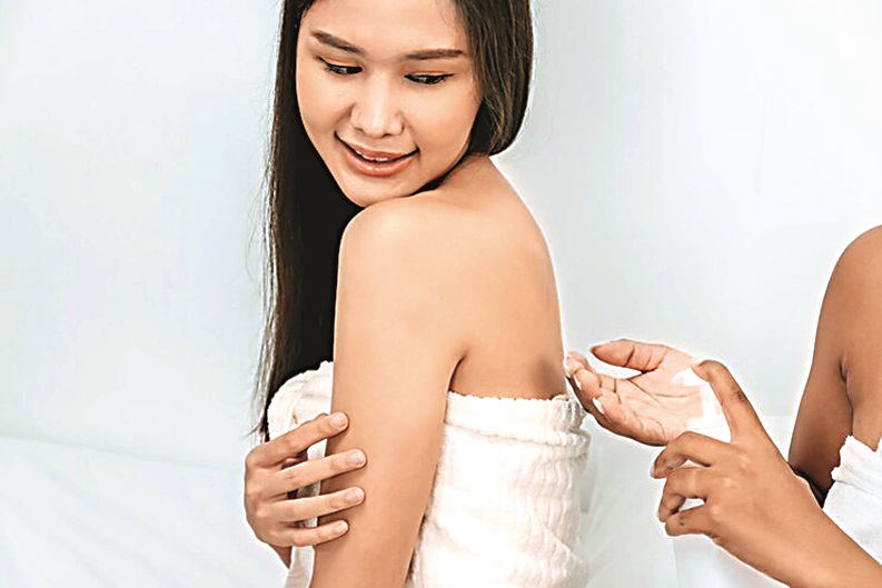 two-beautiful-young-girl-friend-towel-applying-white-body-cream-back