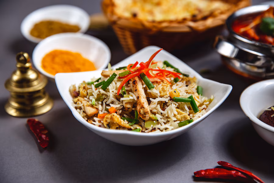 side-view-rice-garnish-with-grilled-chicken-cucumber-carrot-bell-pepper-spring-onion_141793-5070