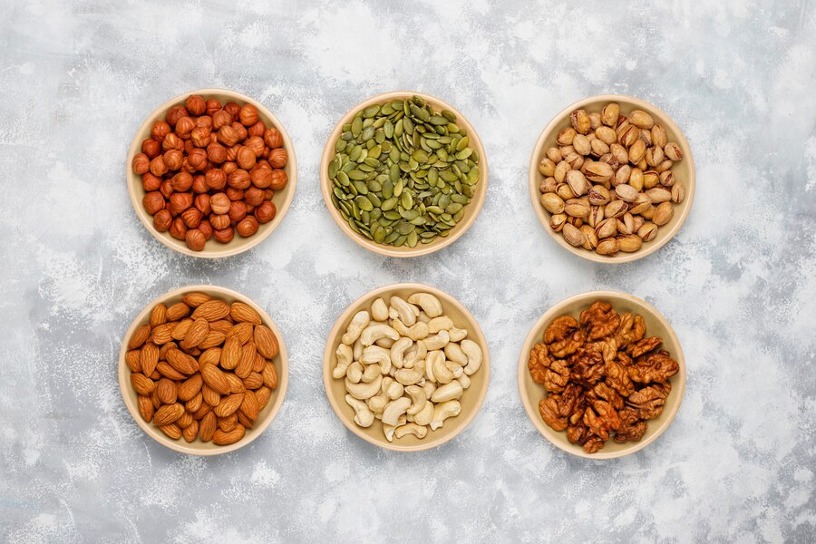 assortment-nuts-ceramic-plates-cashew-hazelnuts-walnuts-pistachio-pecans-pine-nuts-peanut-raisins-top-view_114579-4873