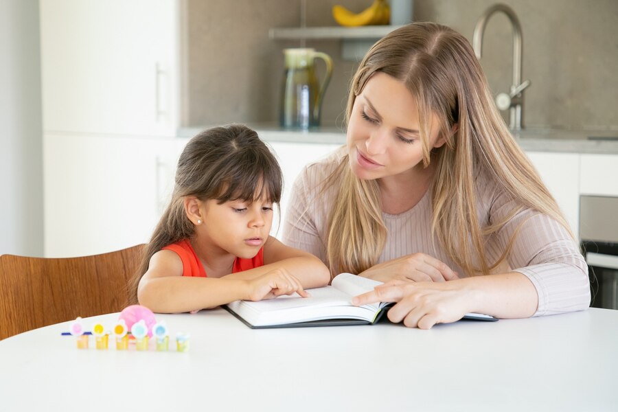 pretty-mom-reading-book-with-daughter-kitchen_74855-8172
