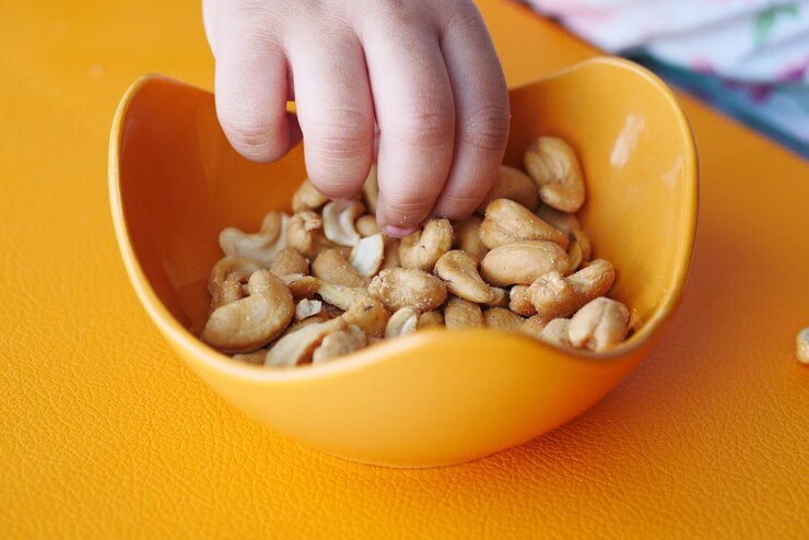 child-hand-pick-peanuts-bowl-table_260672-17435