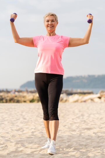 front view elder woman holding up weights while working out  