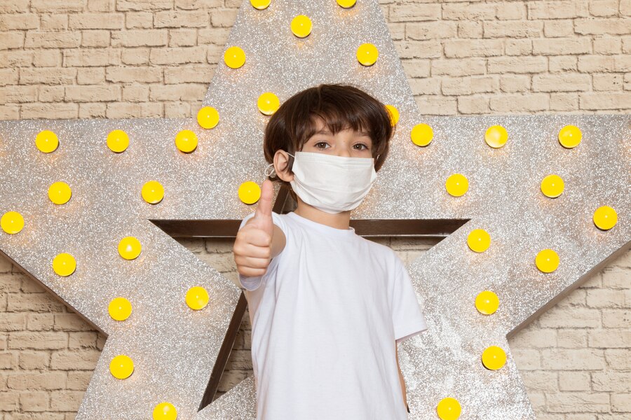 front view cute little kid white t shirt dark jeans white sterile mask star designed yellow stand light background  